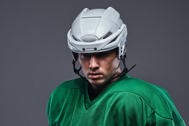 Close-up portrait of a professional hockey player in a protective sportswear and helmet. Isolated on a gray background.