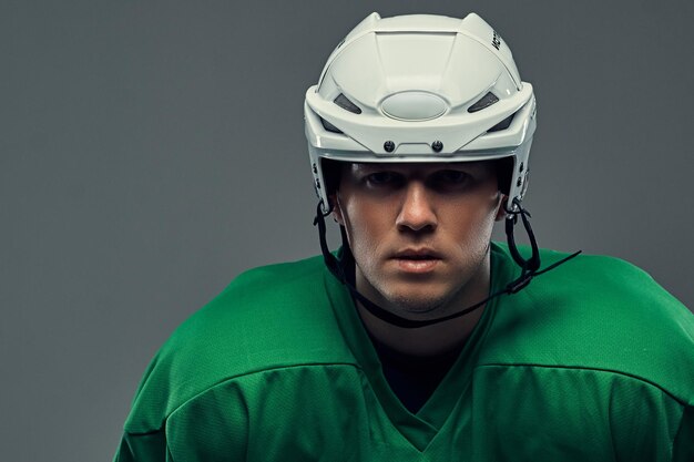 Крупным планом портрет профессионального хоккеиста в защитной спортивной одежде и шлеме. Изолированные на сером фоне.