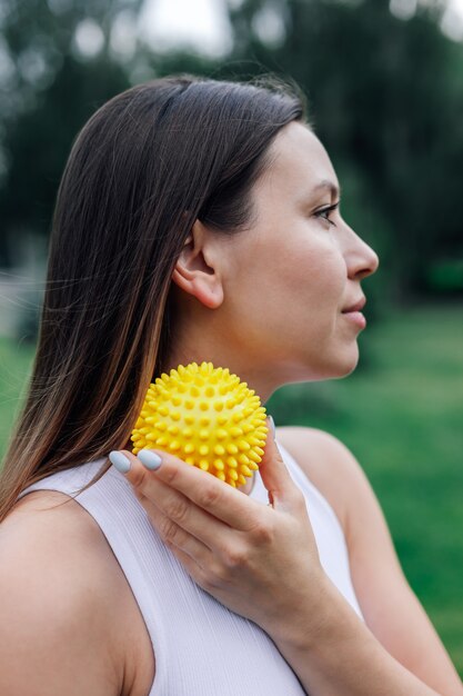 Close  up portrait in profile of young woman face blured with spiky massage ball for myofascial rele...