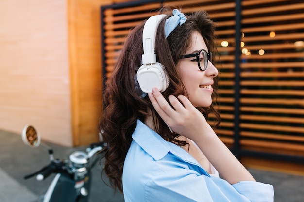 Close-up portrait of romantic curly girl in big earphones wearing golden ring