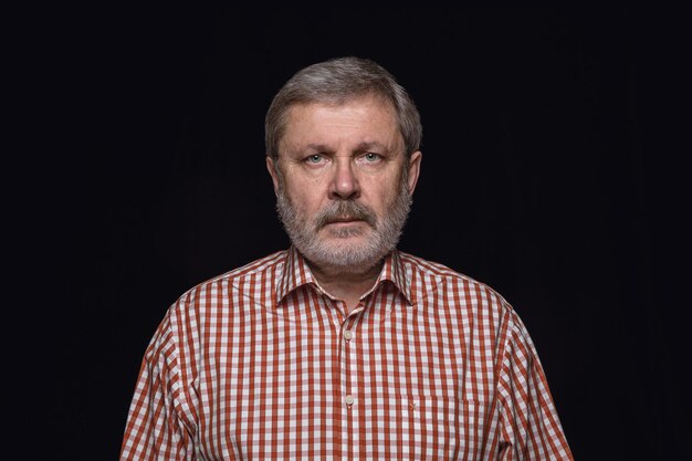 Close up portrait of senior man isolated on black studio background