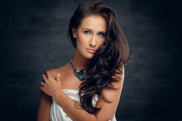 Close up portrait of sensual brunette female in white bra on grey background.