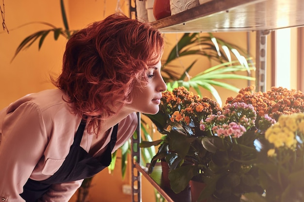 Free photo close-up portrait of a sensual female florist, breathes a pleasant smell of fresh flowers.