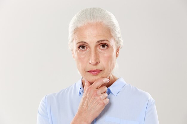 Close-up portrait of serious beautiful old woman, touching her chin