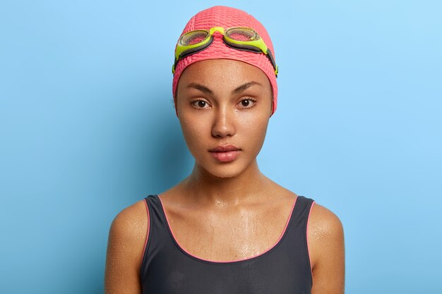 Close up portrait of serious professional swimmer, has wet skin after swimming in swim pool