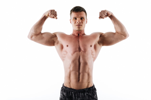 Close-up portrait of serious strong sports man showing his biceps