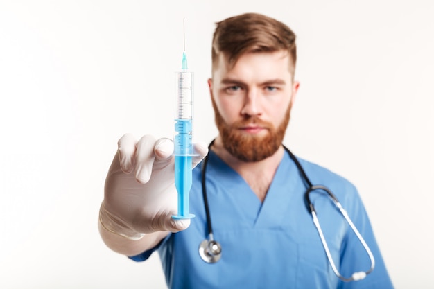Close up portrait of a serious surgeon holding a syringe