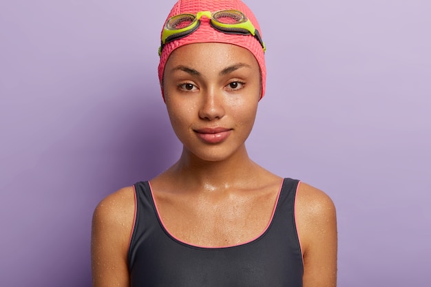 Close up portrait of serious wet dark skinned young woman has calm facial expression