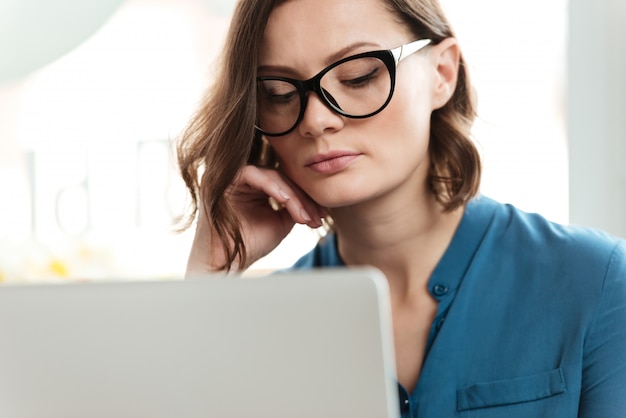 眼鏡の深刻な若い女性の肖像画を閉じる