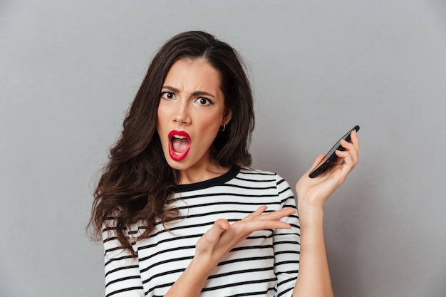 Close up portrait of a shocked girl holding mobile phone