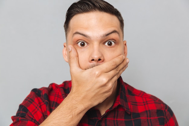 Close up portrait of Shocked man covering his mouth