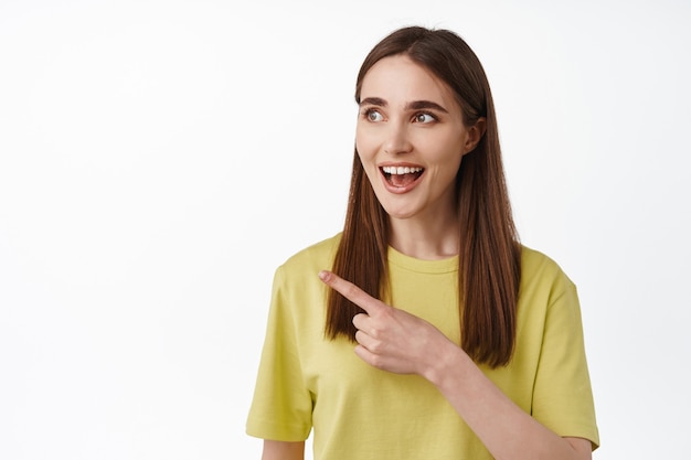 Close up portrait of smiling amazed 20s girl, gasping fascinated with something cool on white.