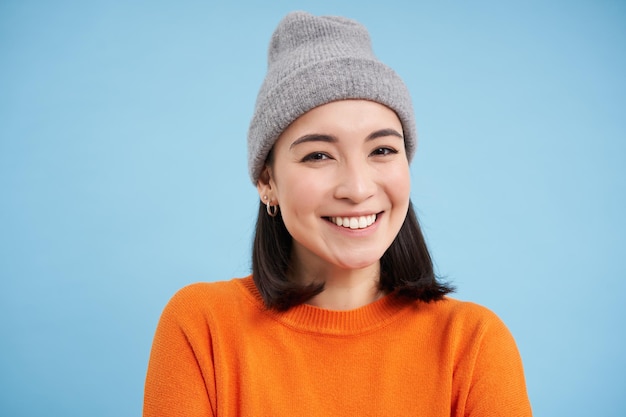Close up portrait of smiling beautiful young woman asian girl in hat looking happy and candid at cam