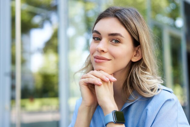 Close up portrait of smiling blond woman student with digital watch looking happy at camera sitting