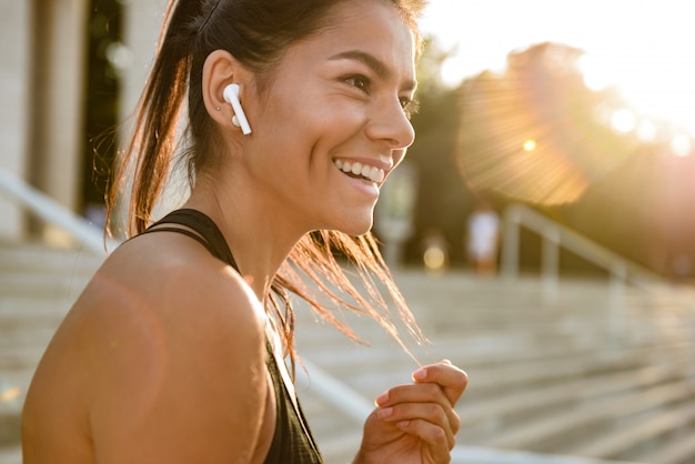 Close up portrait of a smiling fitness woman in earphones
