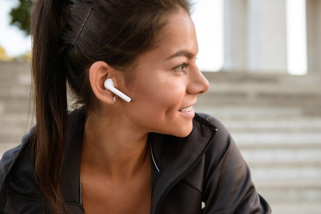 Close up portrait of a smiling fitness woman in earphones