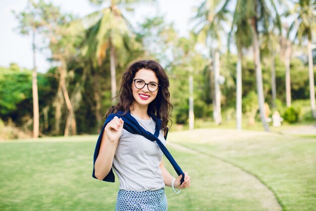 Close-up portrait of a smiling girl with dark short hair and black glasses