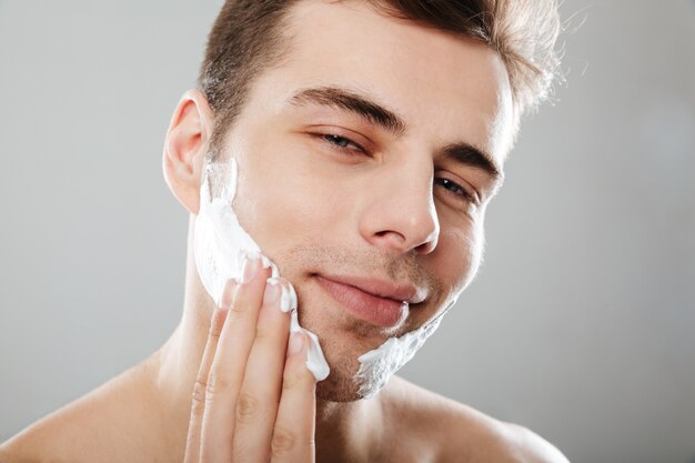 Крупным планом портрет улыбающегося человека, применяя пены для бритья