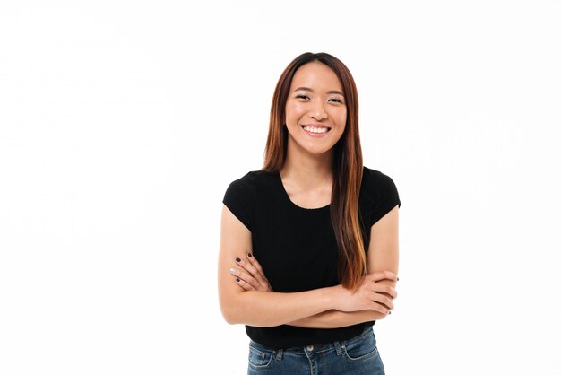 Close-up portrait of smiling young asian girl standing with crossed hands, looking at camera