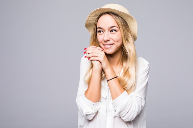 Close up portrait of a smiling young woman in hat looking away at copy space isolated over gray wall