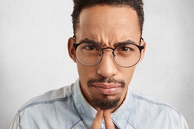 Close up portrait of strict serious male boss, wears big round eyewear