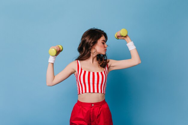 Close-up portrait of strong slim woman showing biceps