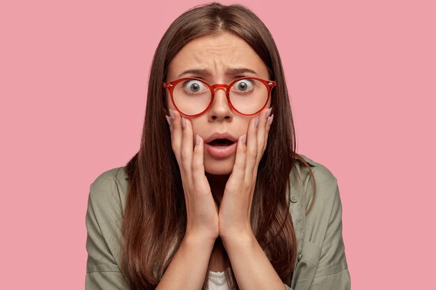 Close up portrait of stunned student posing against the pink wall