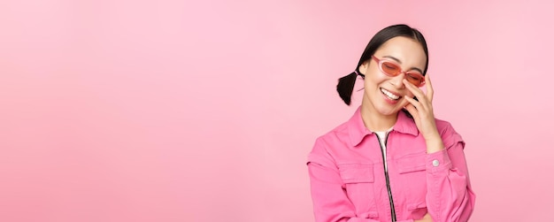 Close up portrait of stylish asian woman in sunglasses smiling looking flattered laughing coquettish