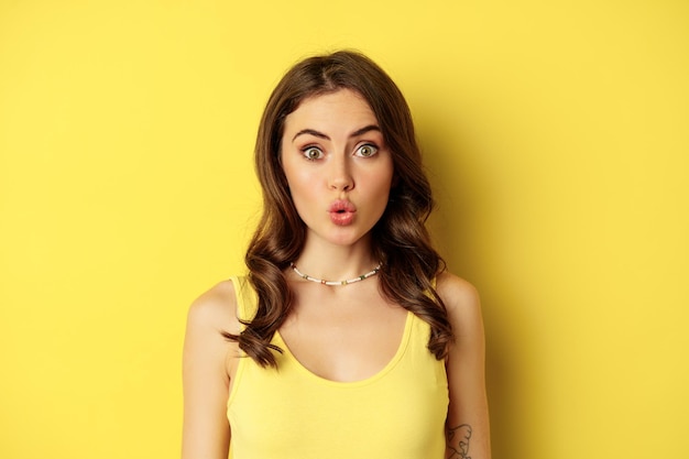 Close up portrait of stylish brunette girl looking amazed wow face showing excitement and surprise i...