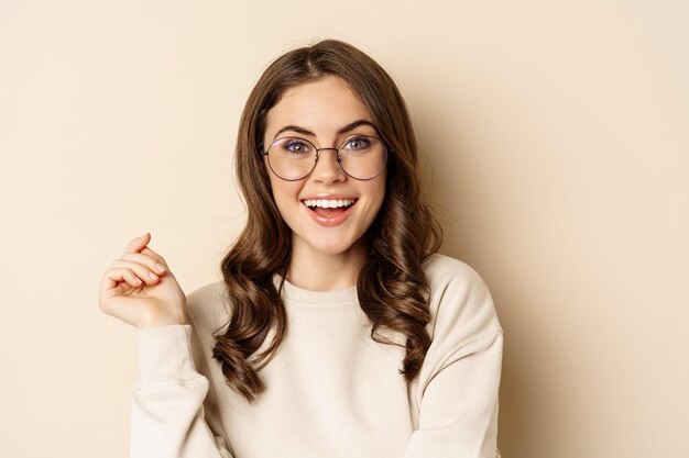 Close up portrait of stylish brunette woman in glasses laughing and smiling posing in eyewear agains...
