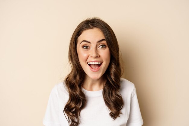 Close up portrait of surprised and excited brunette girl looking amazed reacting impressed and excit...