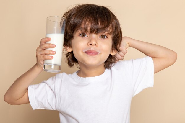 close up, portrait view smiling cute boy adorable drinking white whole milk on pink wall