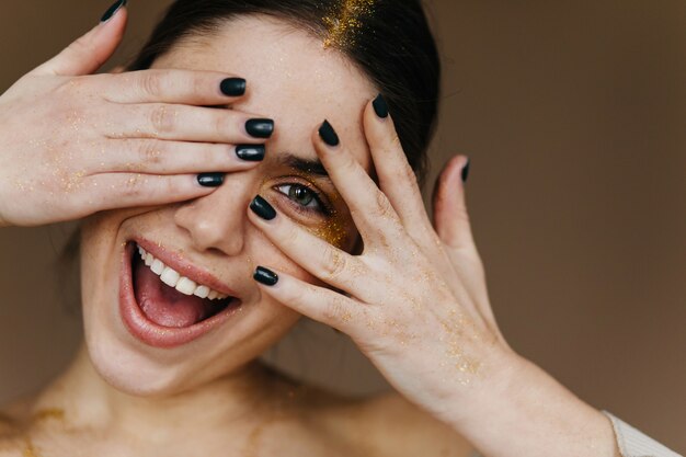 Close-up portrait of white young lady playfully posing. Joyful girl with black manicure laughing