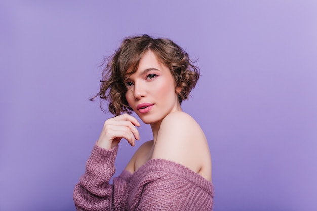 Close-up portrait of winsome woman with curly dark hair. Photo of  young lady isolated on purple wall.