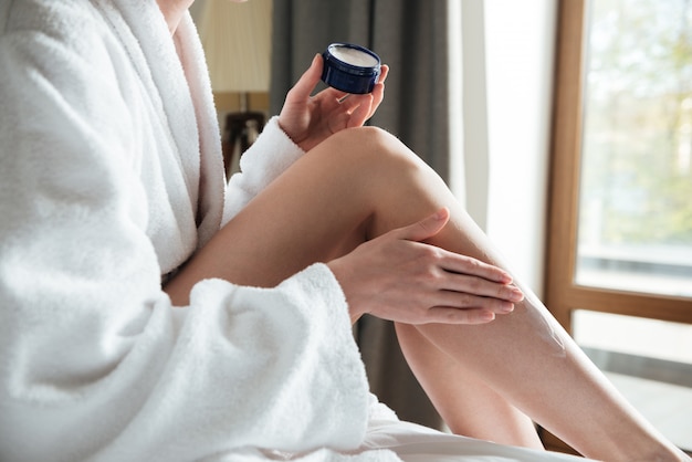 Close up portrait of a woman applying cream on her legs