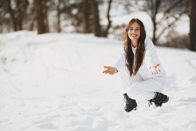 Close-up portrait of woman in black jacket. Woman standing in a forest in snowy day.