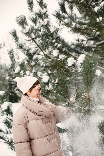 Foto gratuita ritratto del primo piano della donna in una giacca marrone nel parco innevato