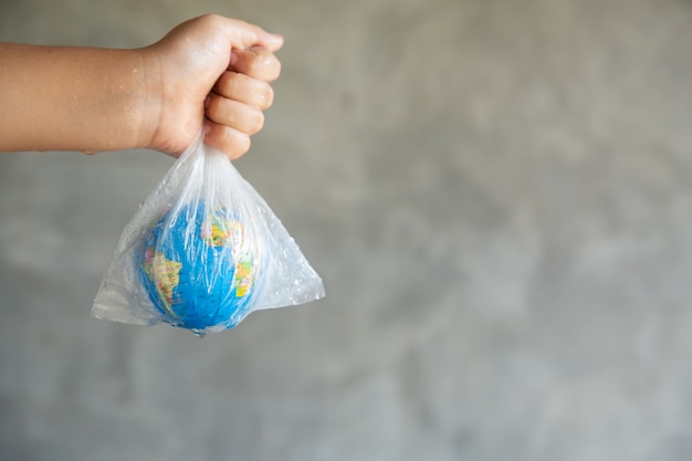 Close-up Portrait of Woman is Holding Global in Her Hands on gray