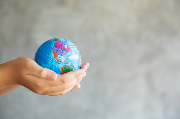 Close-up Portrait of Woman is Holding Global in Her Hands on gray