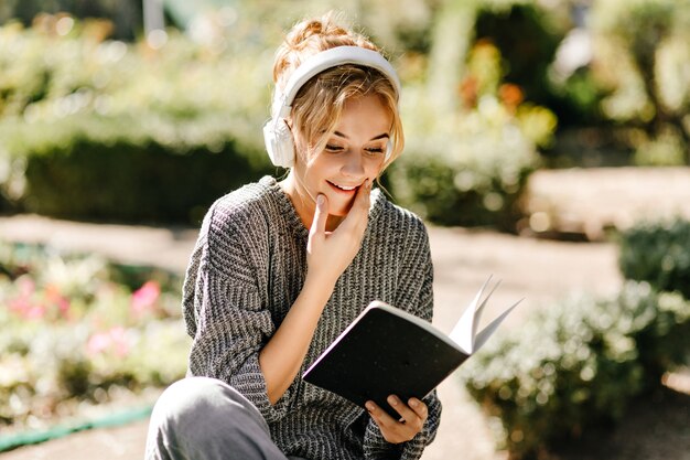 Close-up portrait of woman listening to music and reading a book