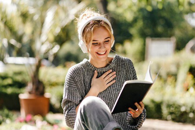 Close-up portrait of woman listening to music and reading a book