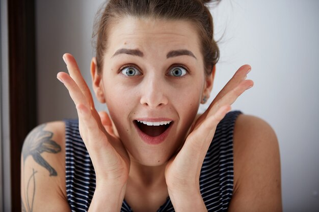 Close up portrait woman looking surprised in full disbelief wide open mouth