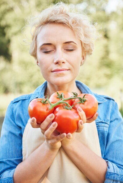 Close up portrait of woman smelling fresh tomatoes