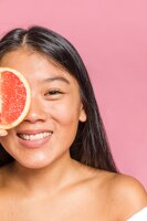 Close-up portrait of woman smiling and a grapefruit