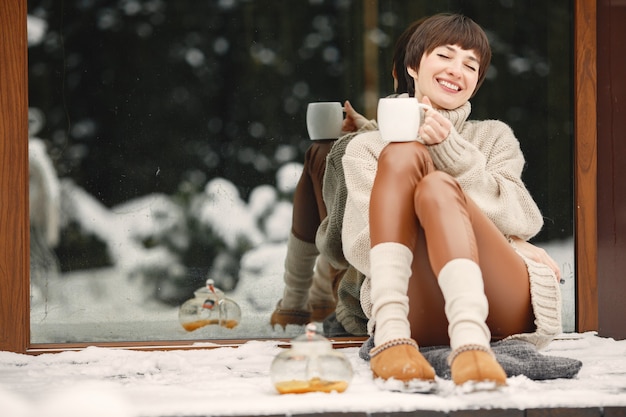 Close-up portrait of woman in white sweater, drinking tea