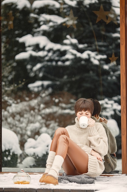 Close-up portrait of woman in white sweater, drinking tea