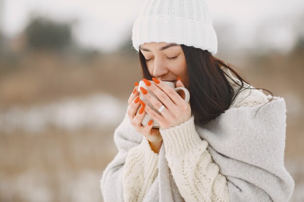 Close-up portrait of woman in white sweater with tea