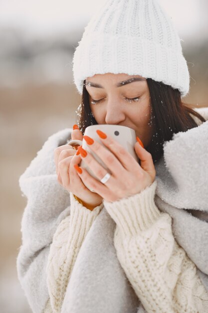 Close-up portrait of woman in white sweater with tea