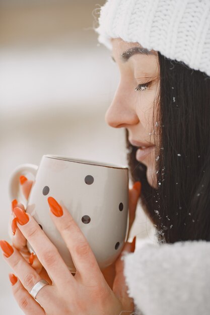 Close-up portrait of woman in white sweater with tea