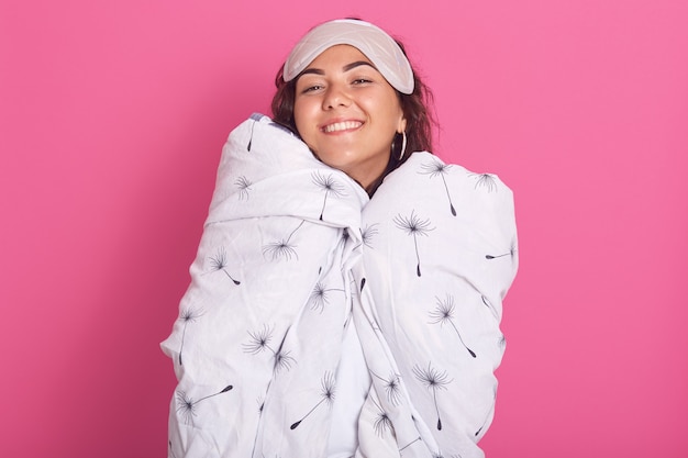 Close up portrait of woman with sleeping mask on her forehead, wrapped white blanket with dandelion